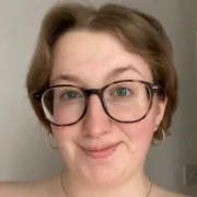 White woman wearing glasses with short mid-brown hair