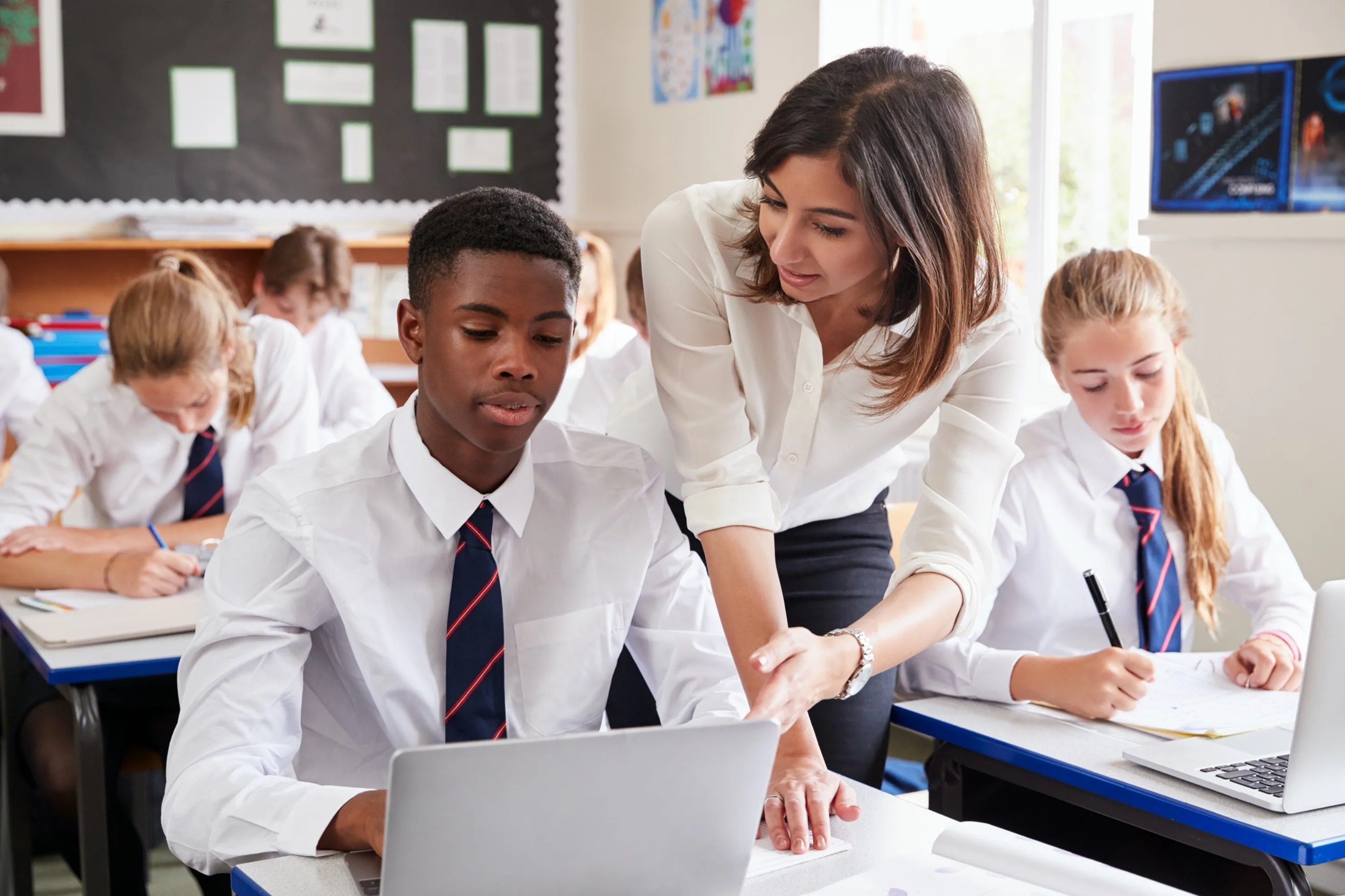 A teacher helps a secondary school pupil in the classroom