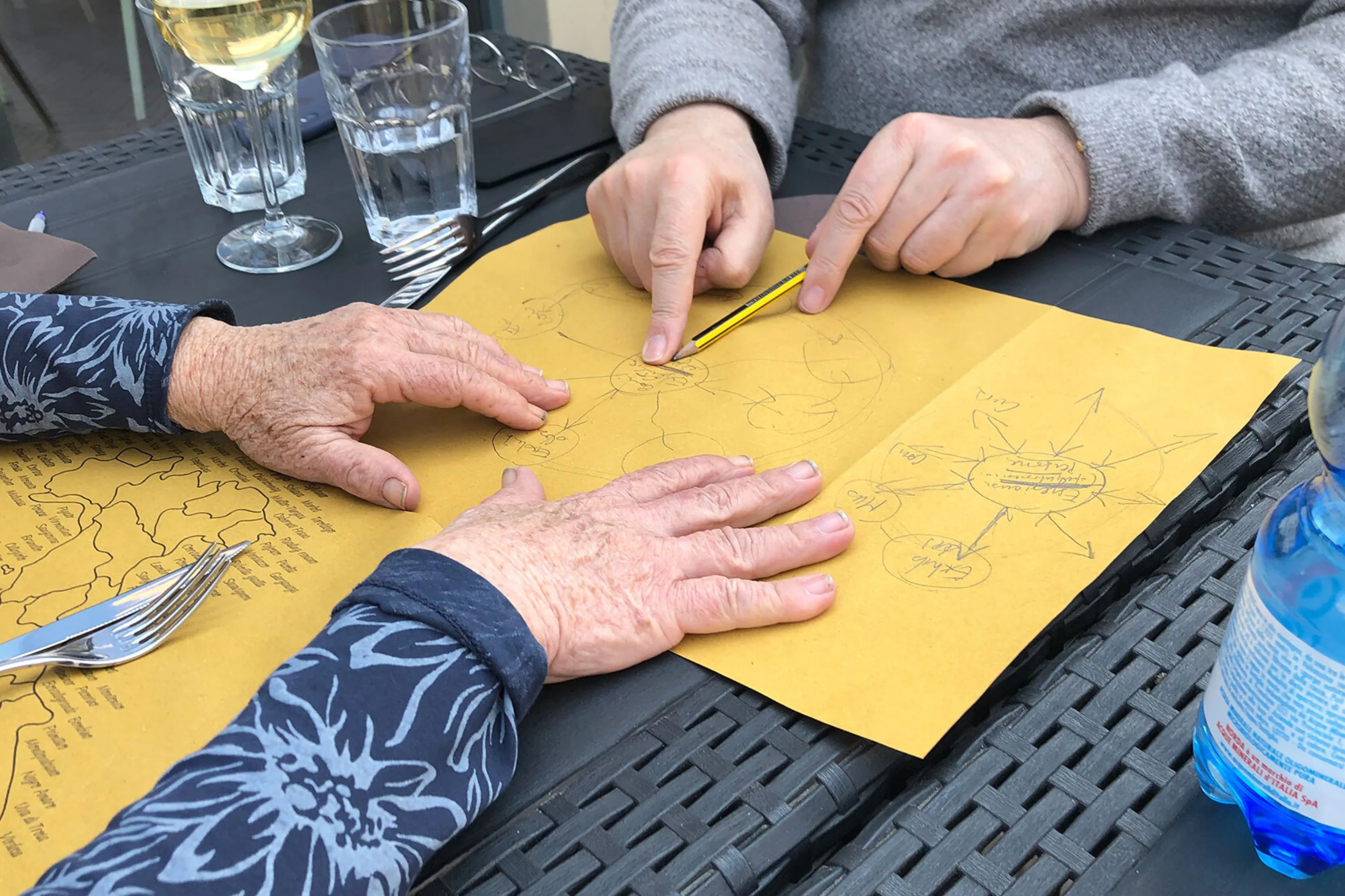 Two people plan a digital strategy on the back of a paper placemat on paper over lunch