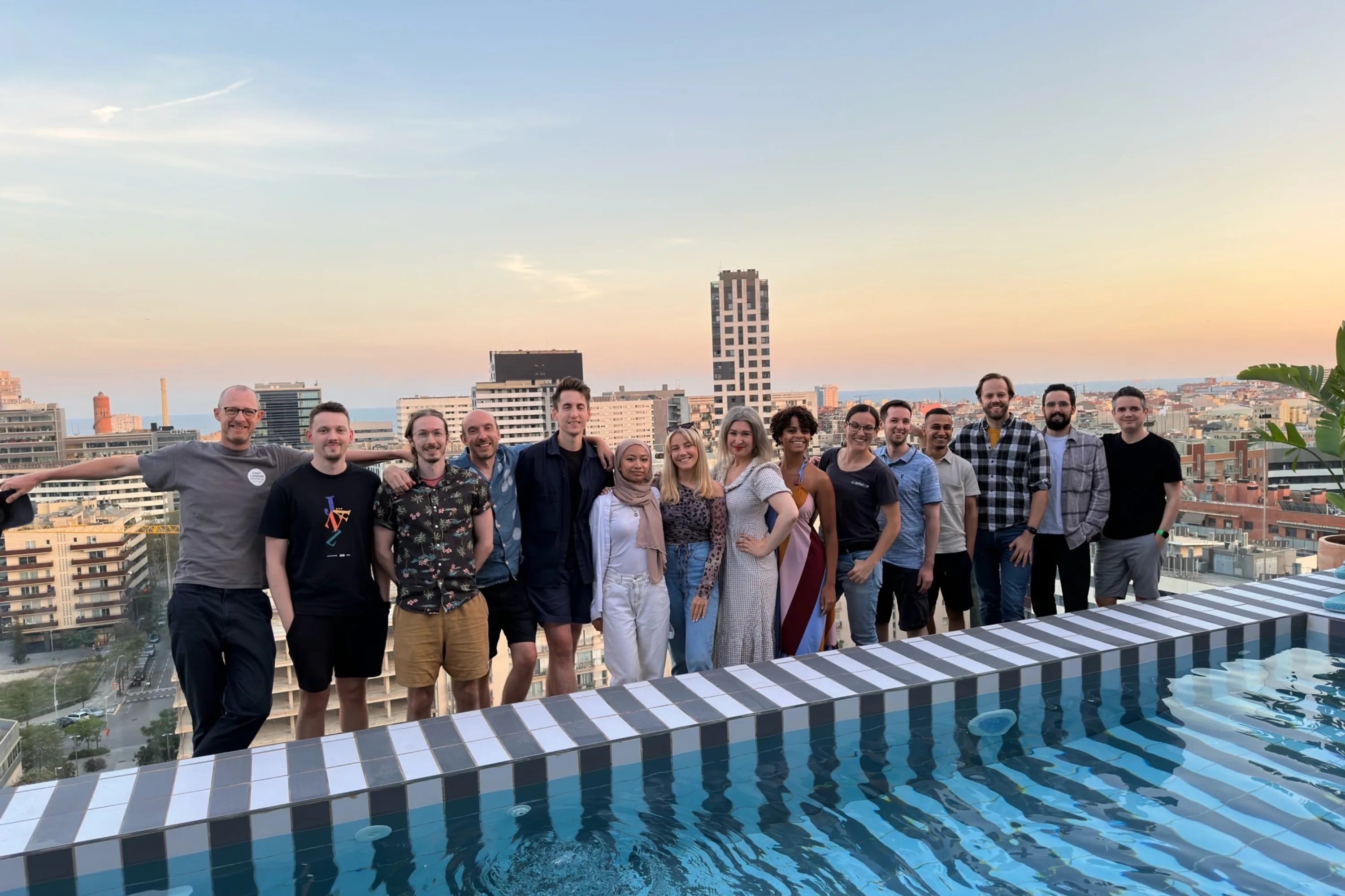 10 men and 5 women line up for a group photo at a rooftop bar