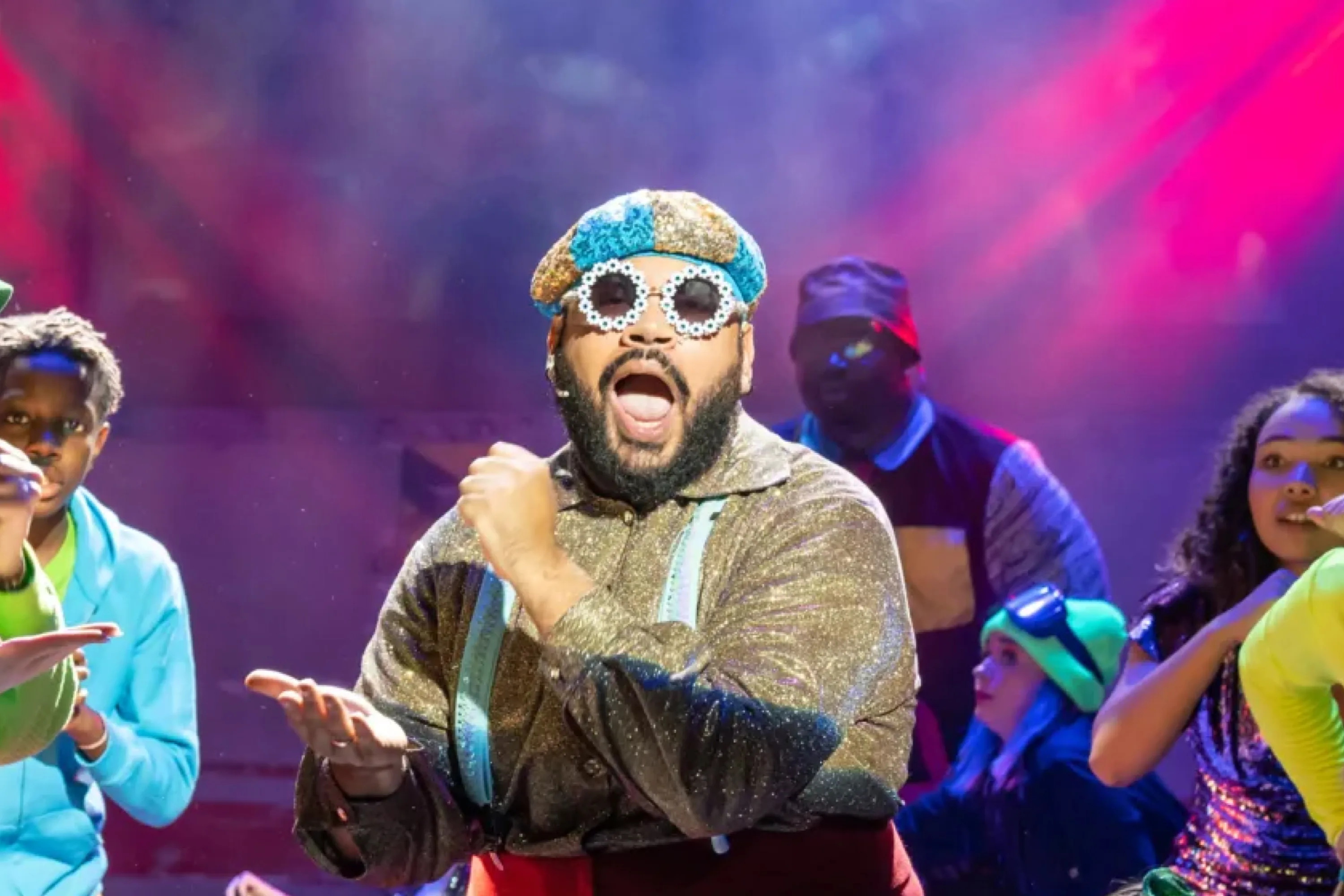 A man sings on stage in 70s disco attire