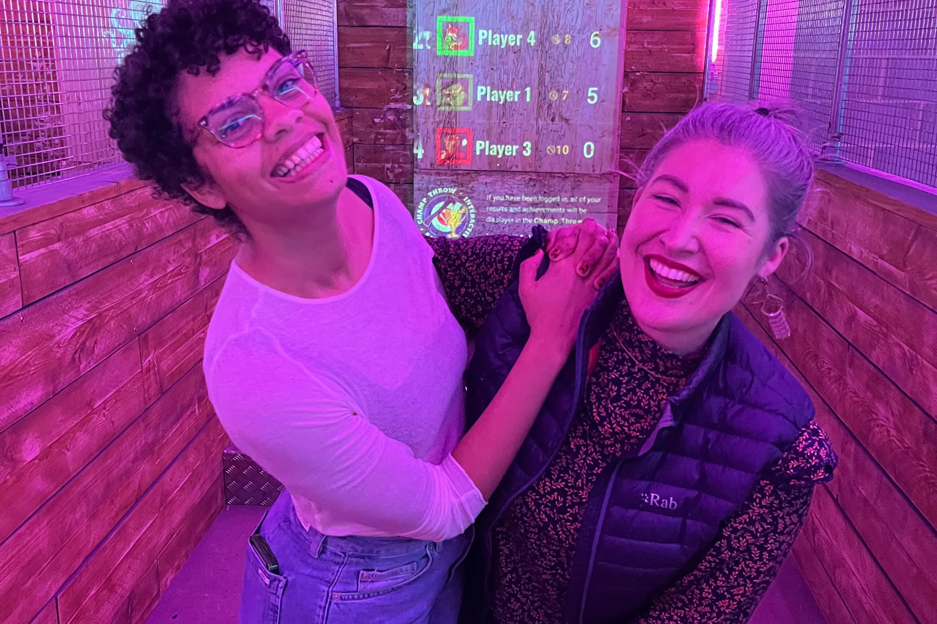 Two laughing women smile with their arms around each other