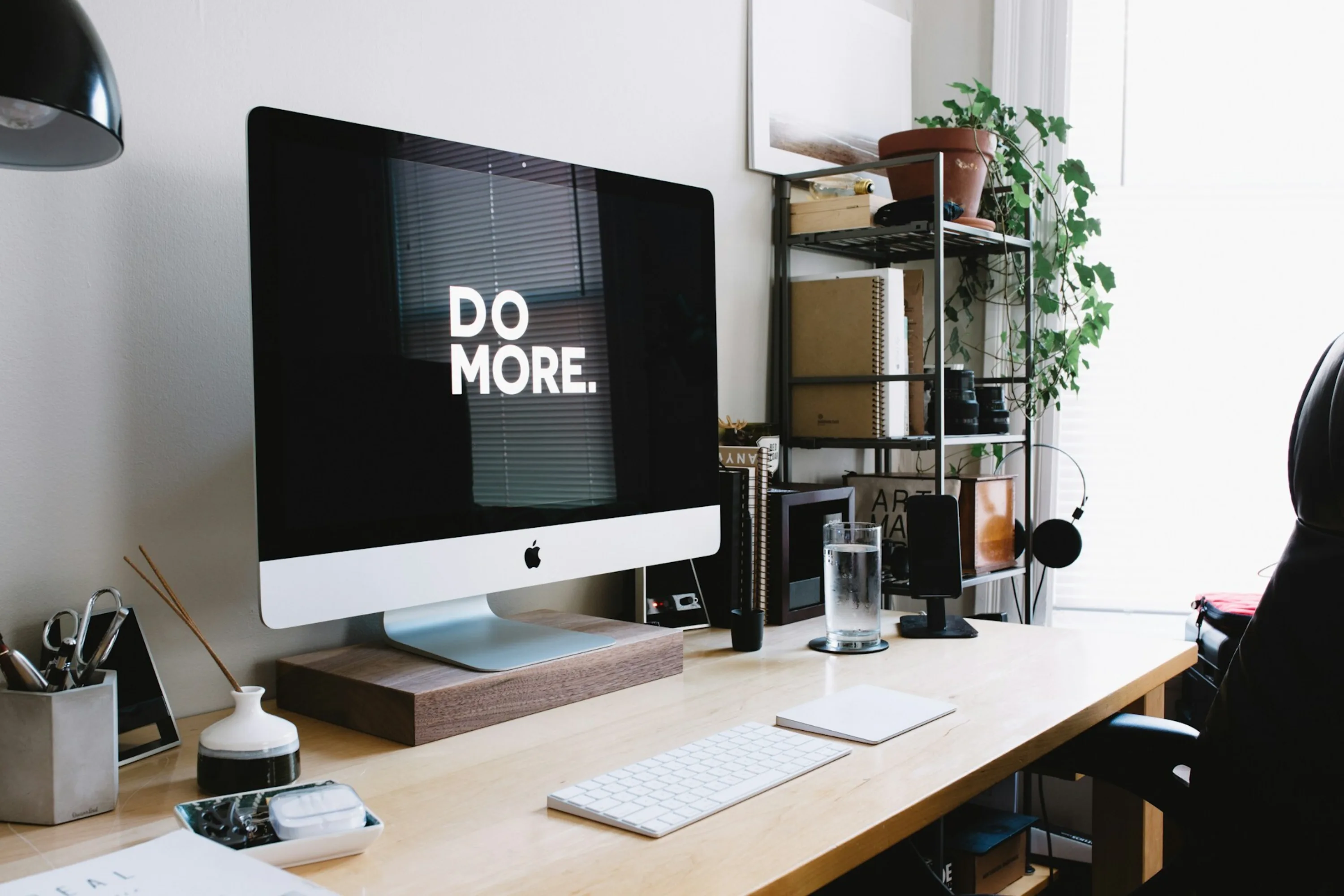 A desk in a home office with a computer screen reading "Do More" in large capital letters.