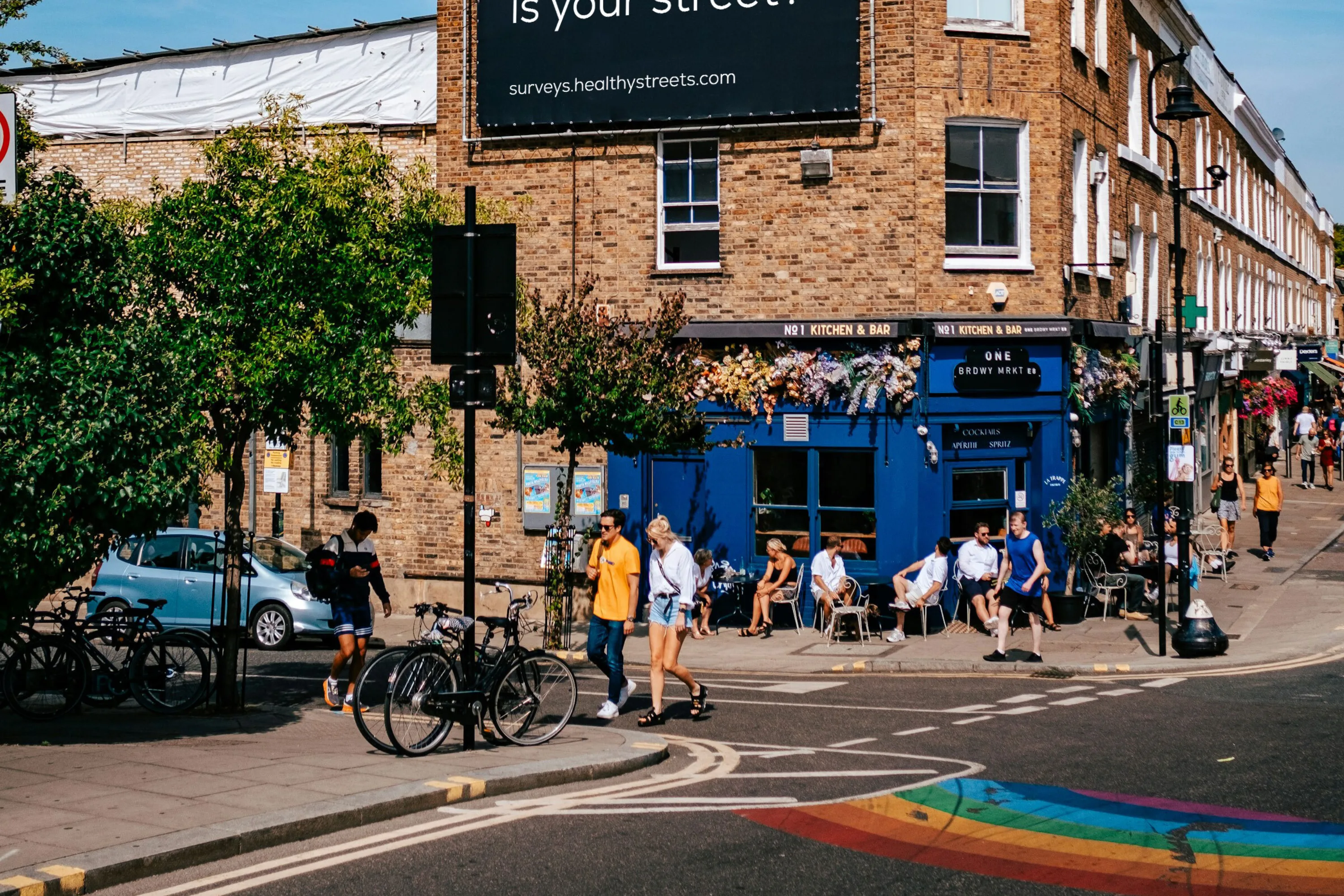 Street corner in summer with a large poster: How healthy is your street?
