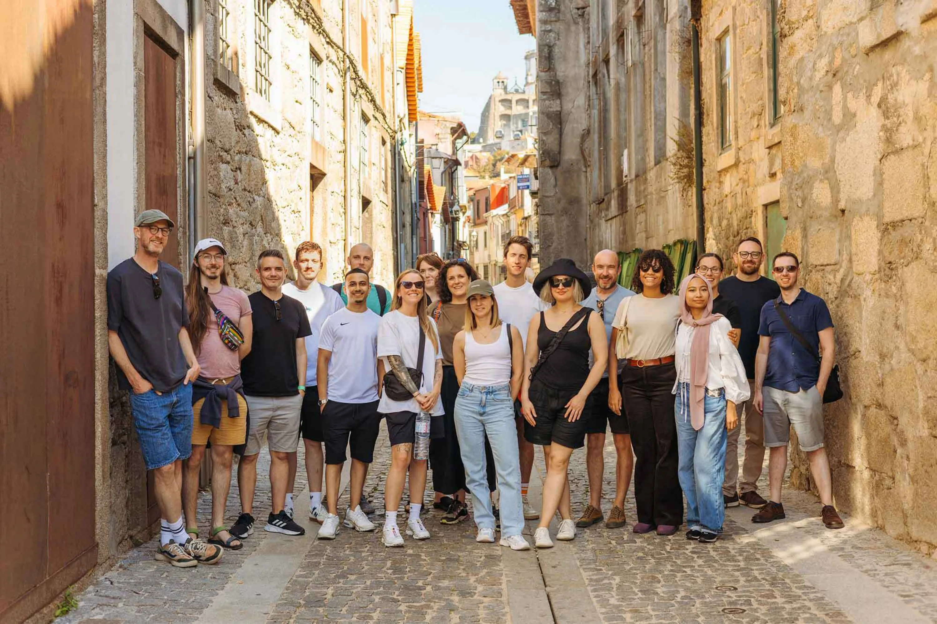 Team photo showing 18 people in a narrow European street in summer