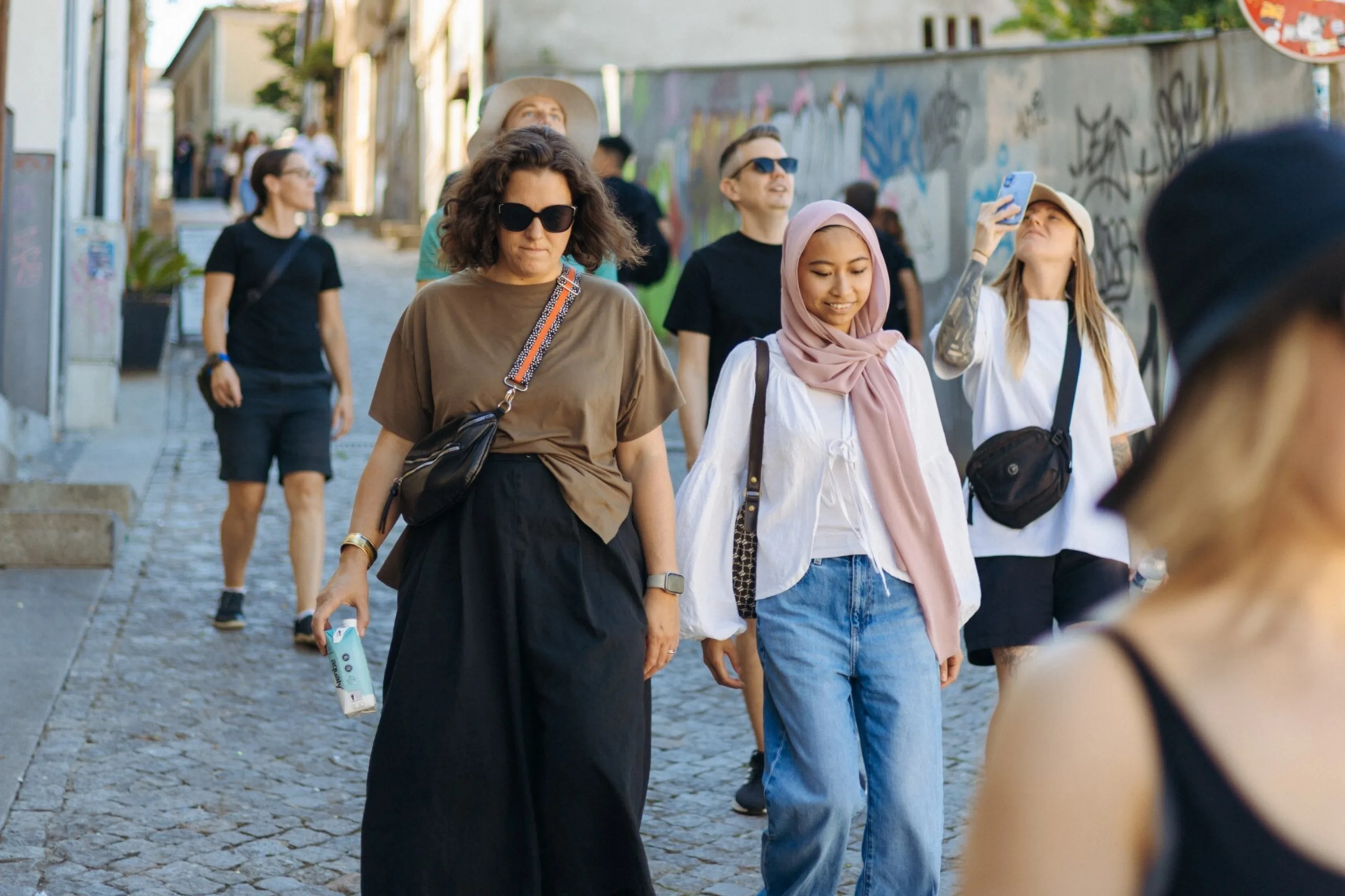 A group of people walk down a cobbled street in Porto