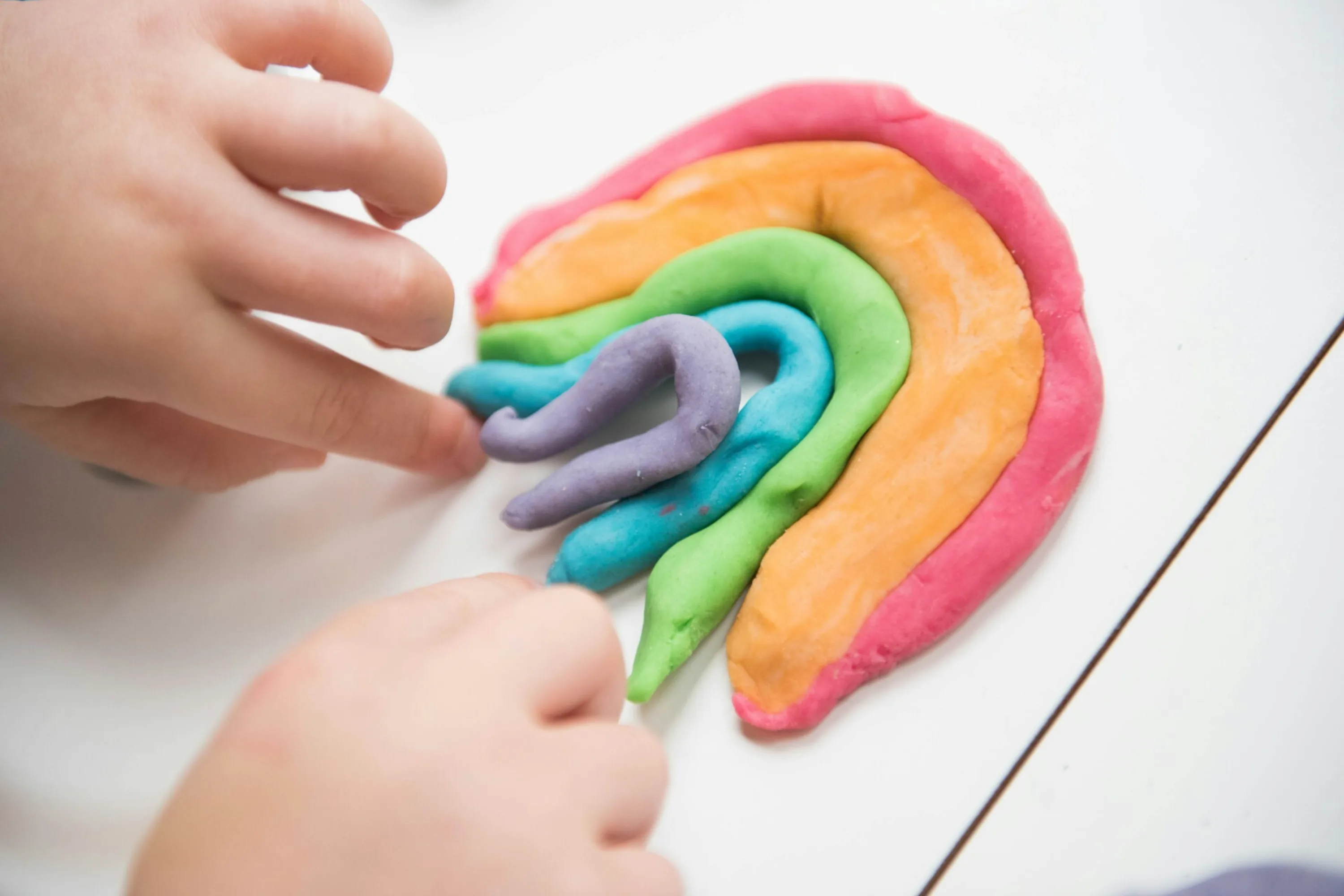 young fingers create a rainbow in colourful modeling clay
