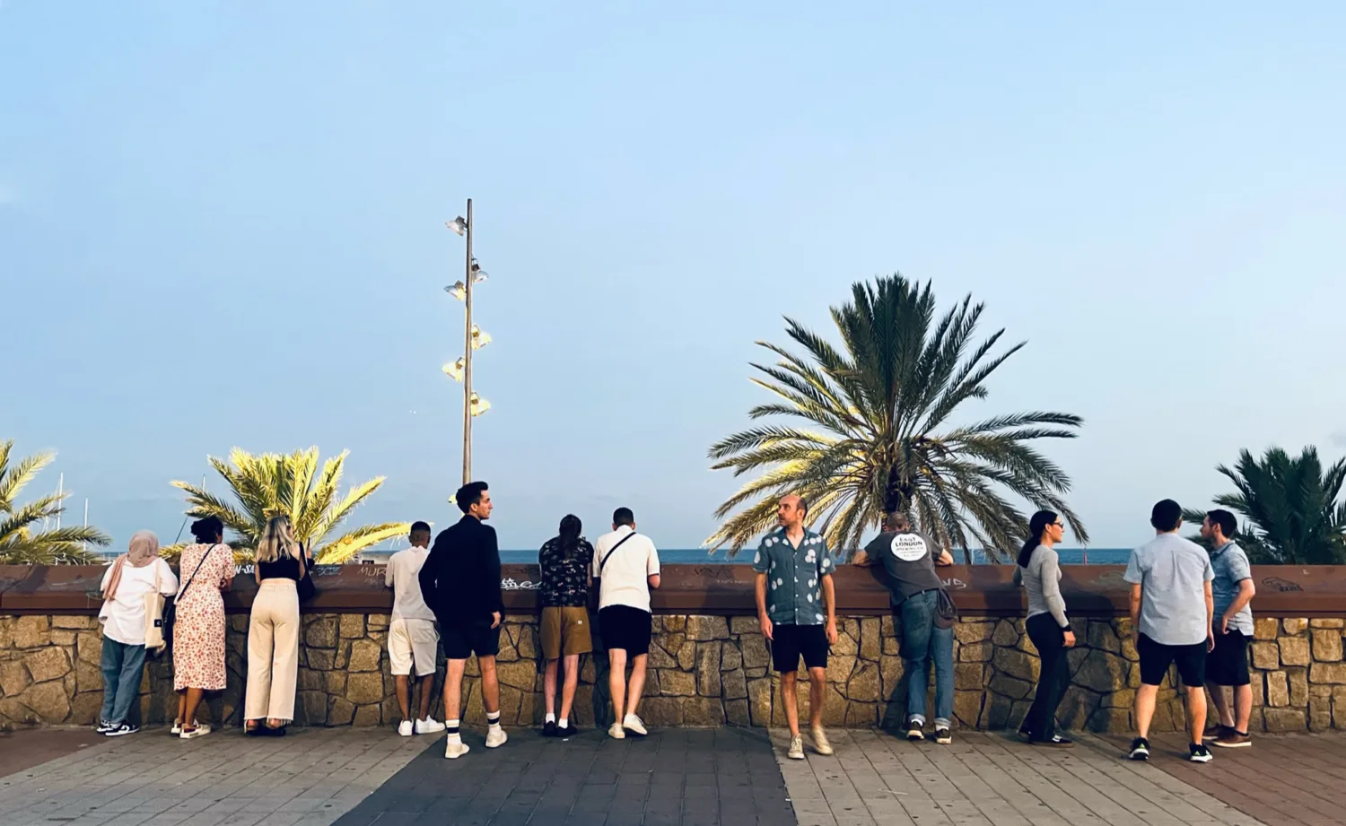 12 people look out at the sea under a clear sky