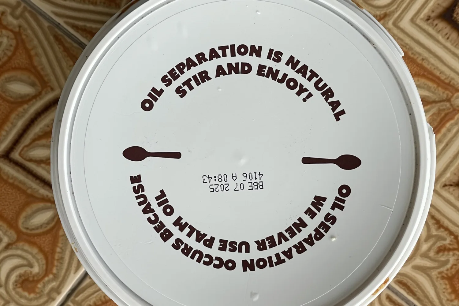 The lid of a tub of Meridian peanut butter, with printed instructions to stir before use.