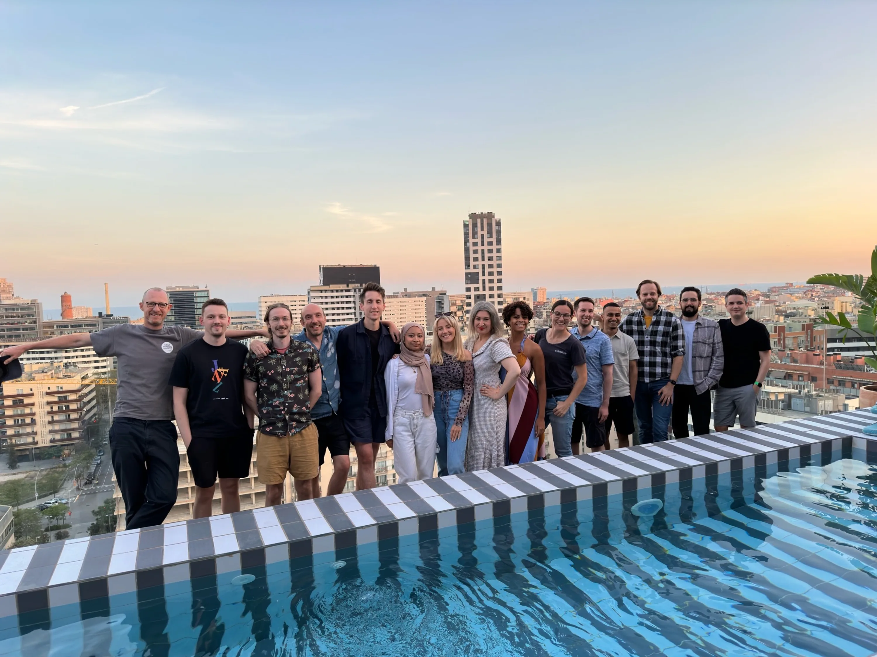 10 men and 5 women line up for a group photo at a rooftop bar
