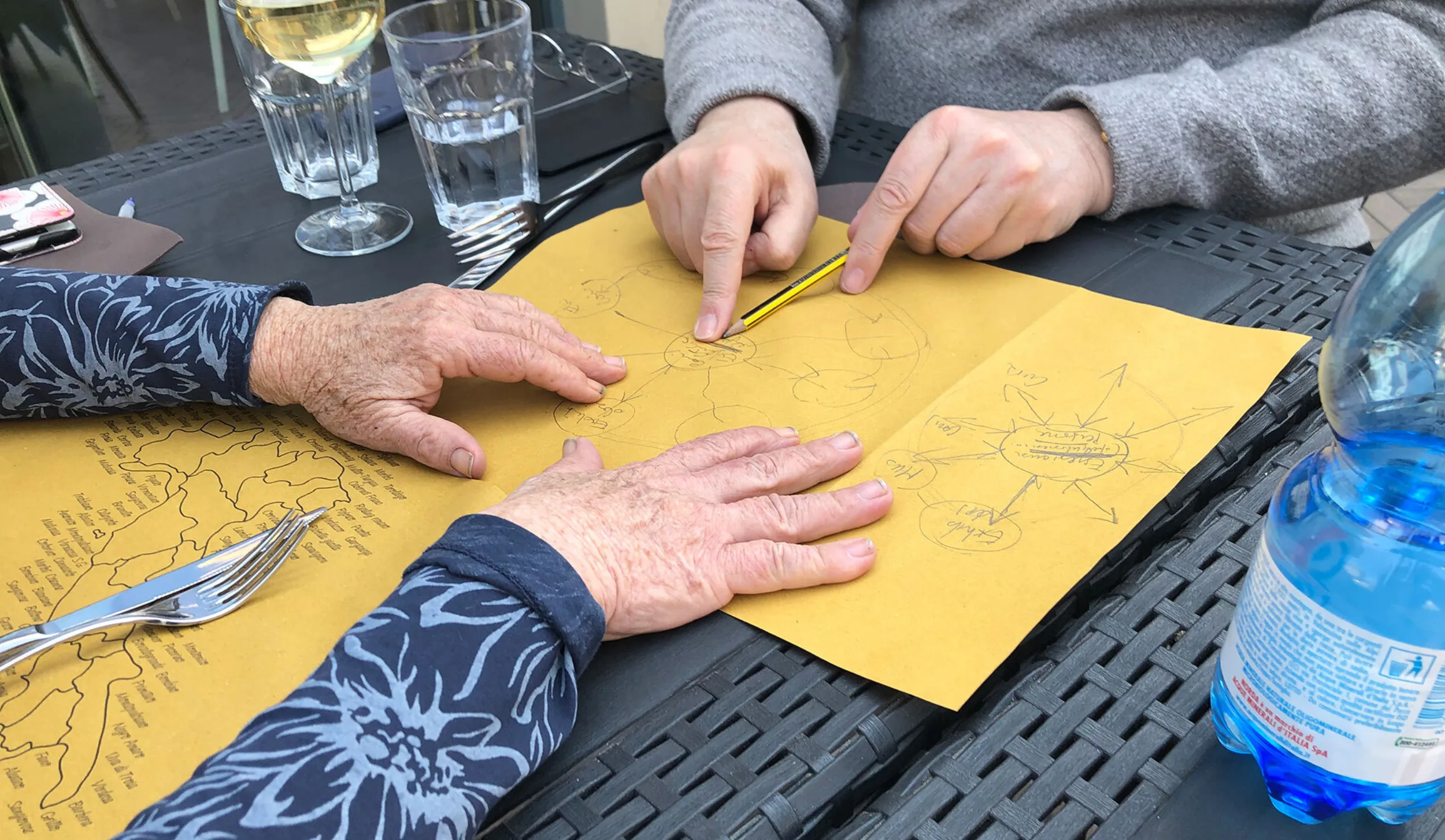 Two people plan a digital strategy on the back of a paper placemat on paper over lunch