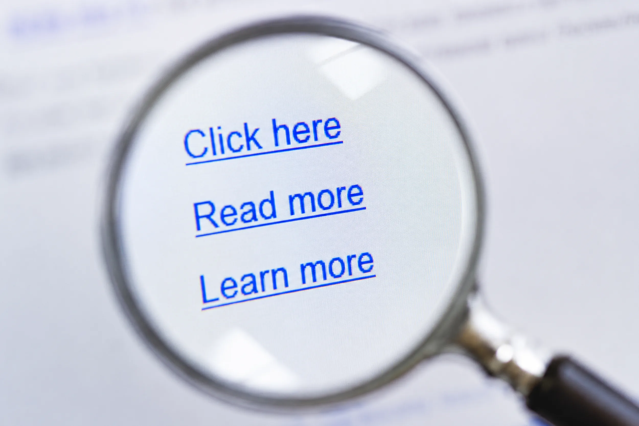Magnifying glass enlarging generic website links labelled “Click here”, “Read more” and “Learn more”.