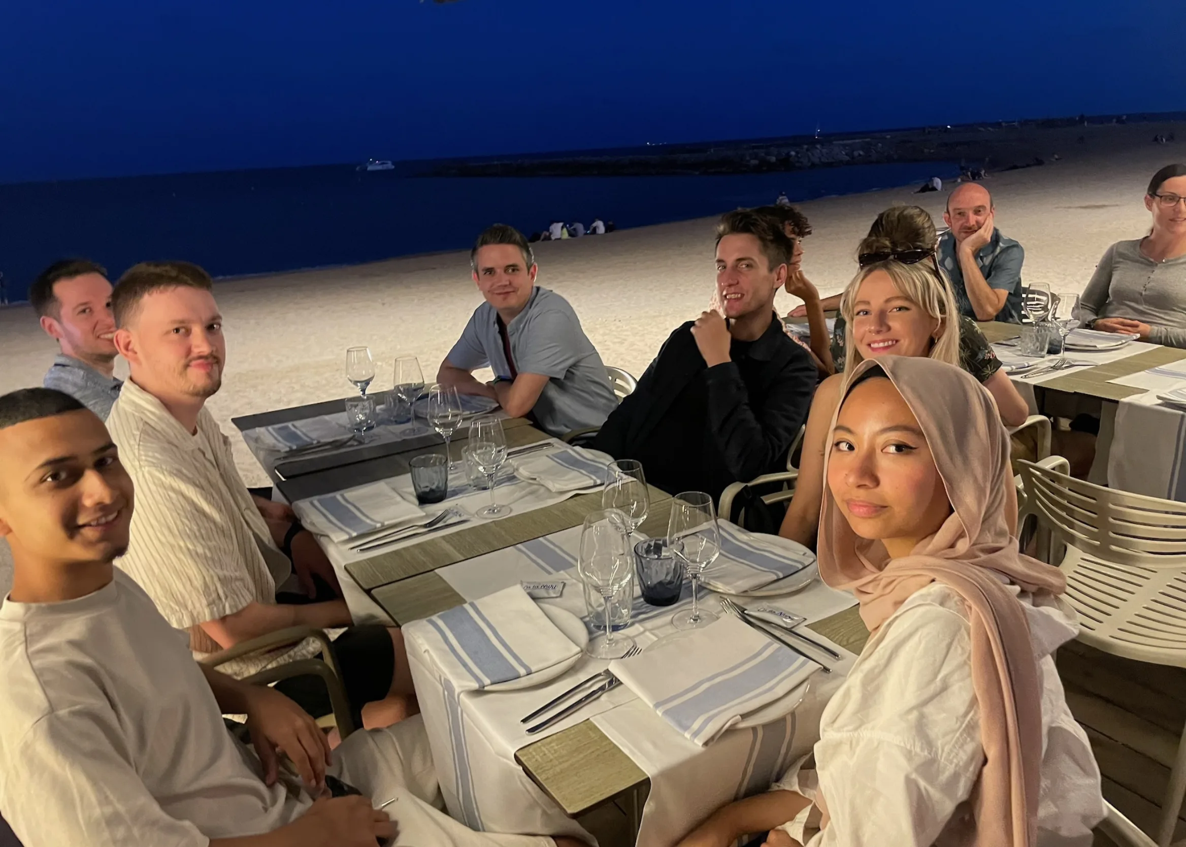 10 people around two tables in a restaurant ton the beach