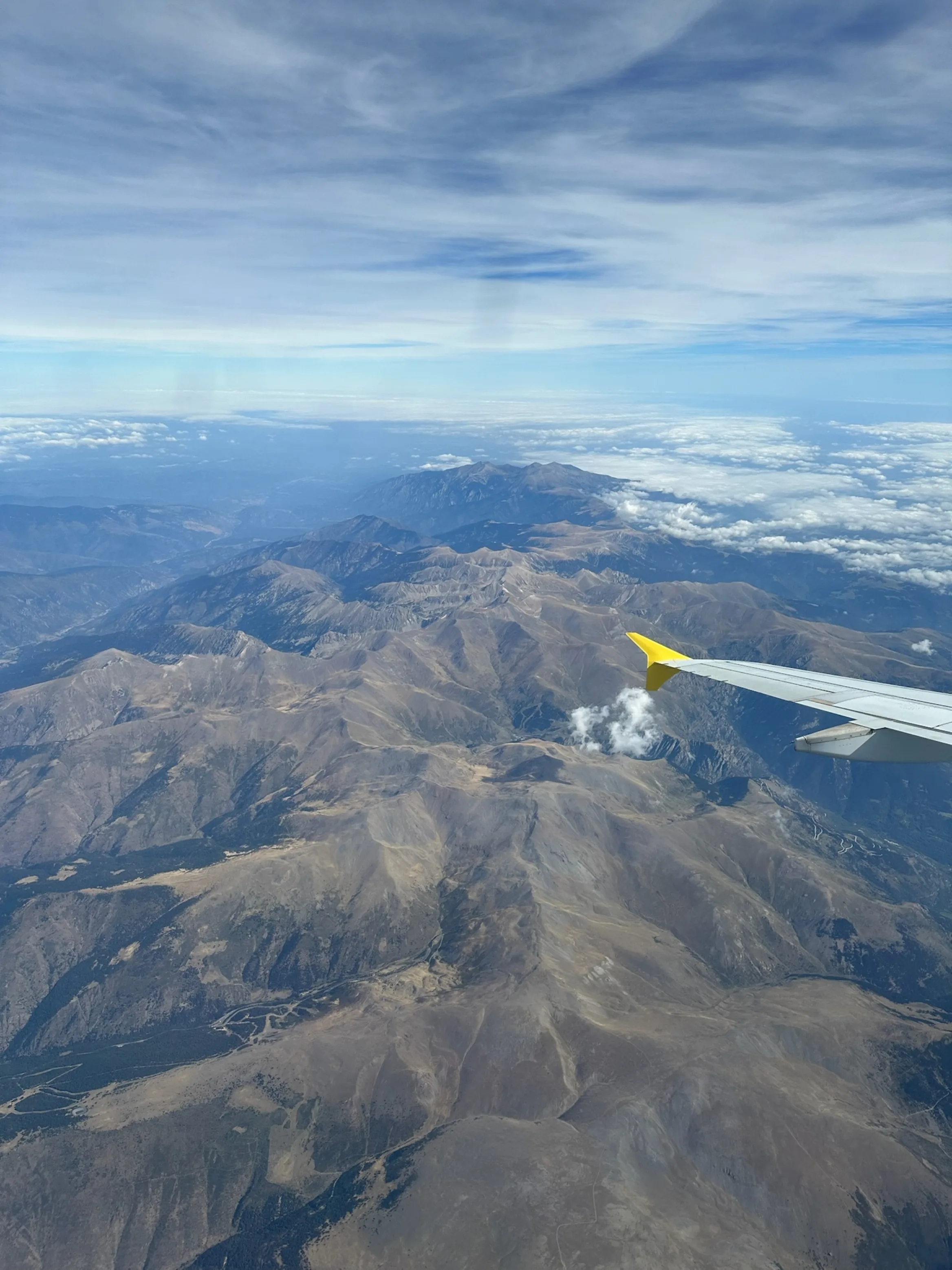 airplane wing seen from inside a plane flying over mountains