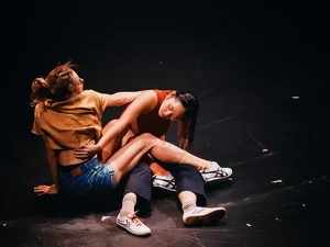 Two young women engage each other in an interpretative dance