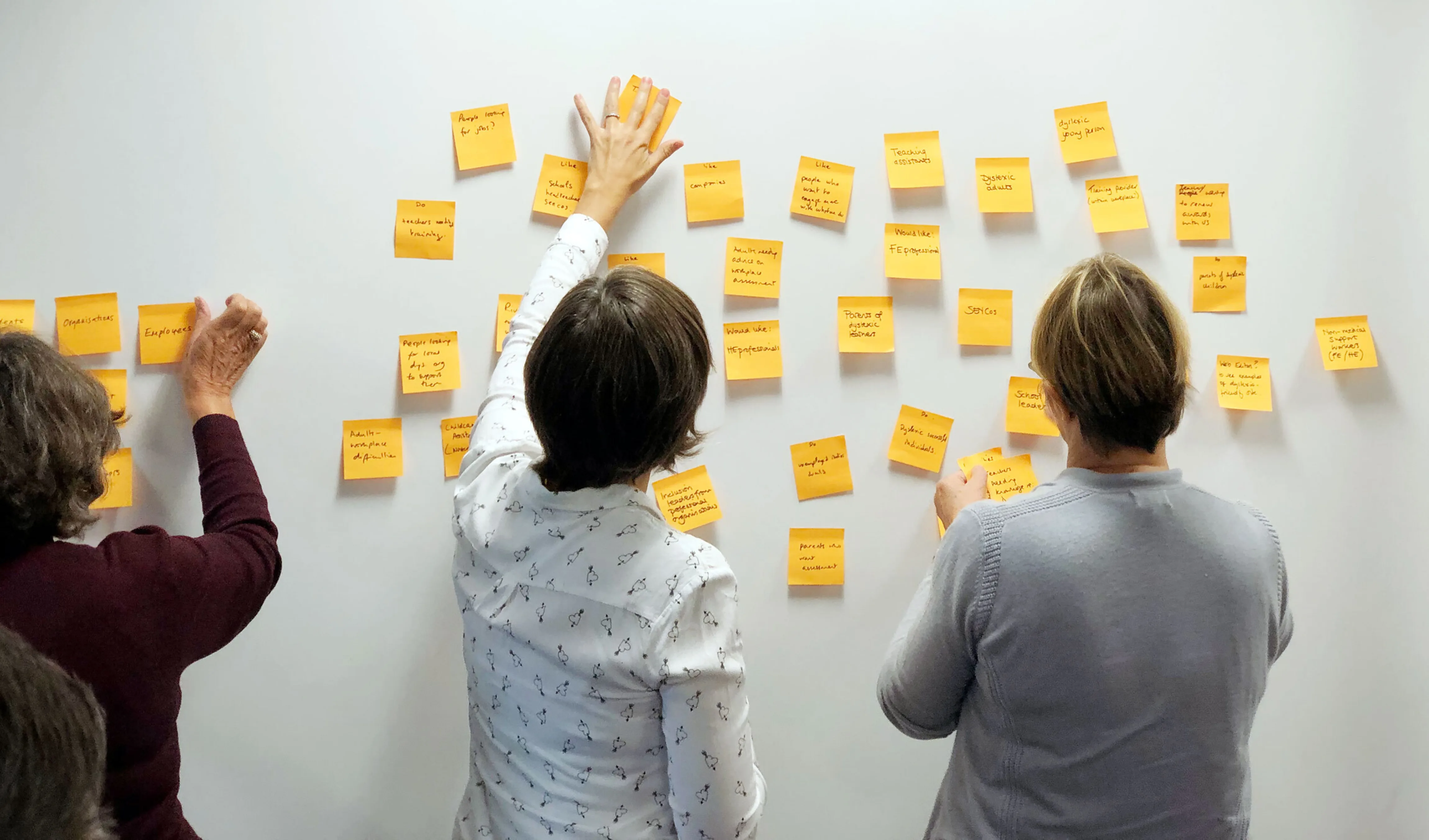 Three women post ideas to the wall on post-it notes