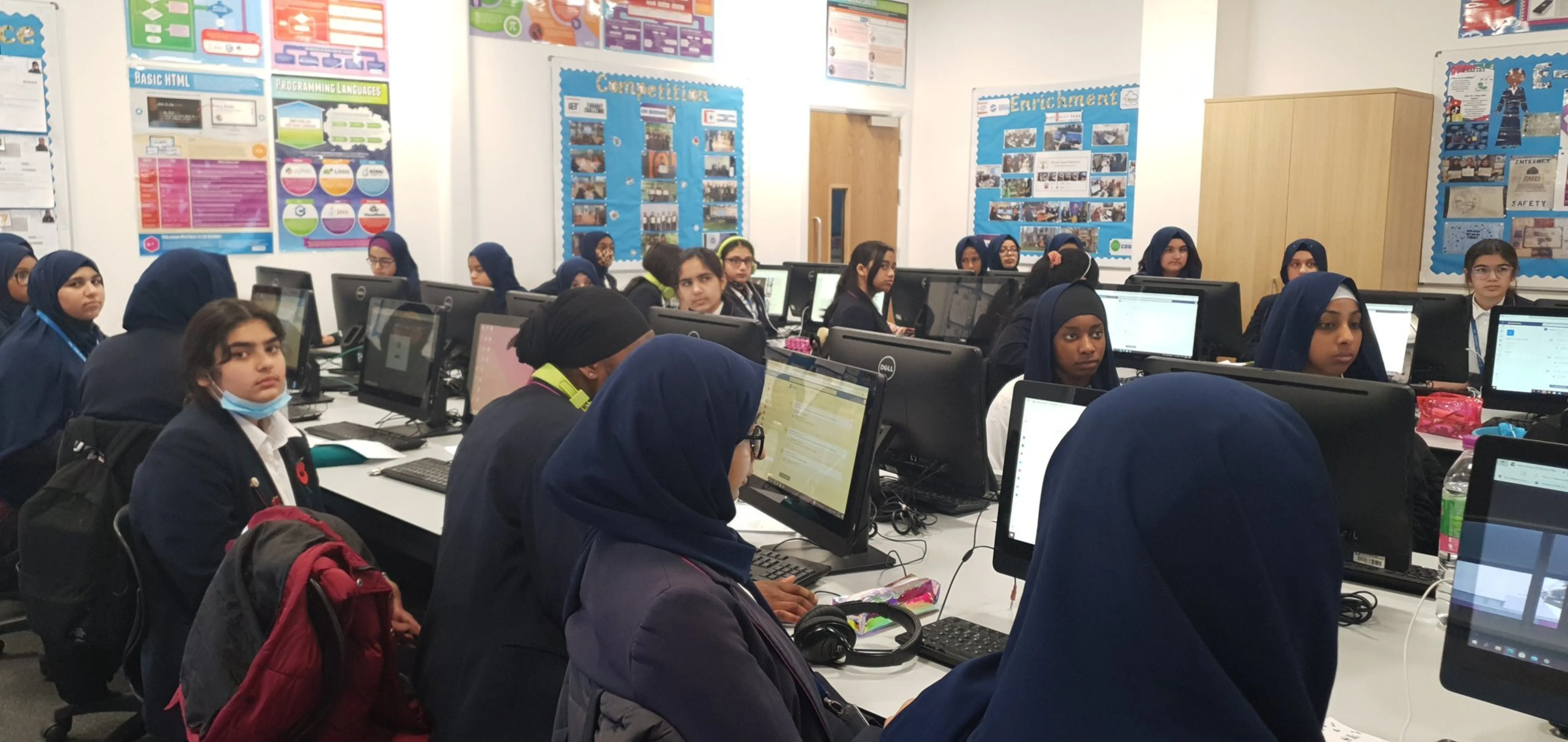 The computer room of an East London secondary school with rows of tables and monitors